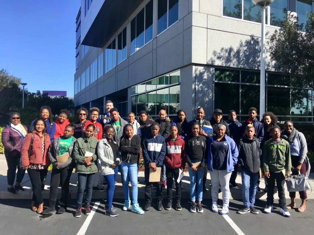 Group of students and chaperones posing outside a modern building during a field trip or educational outing.