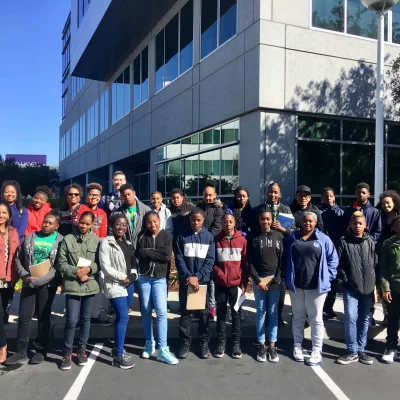 Group of students and chaperones posing outside a modern building during a field trip or educational outing.